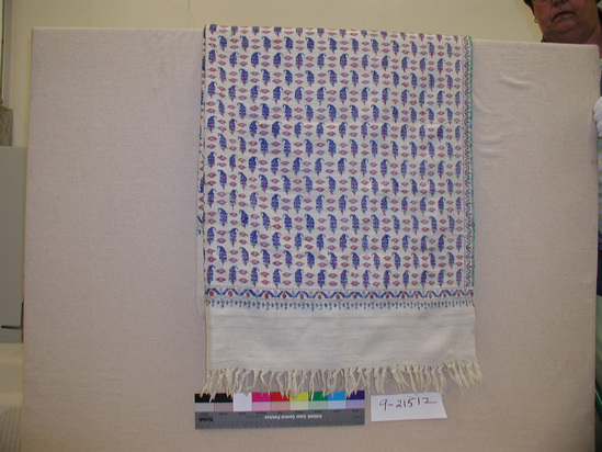 Hearst Museum object titled Shawl, accession number 9-21512, described as Shawl; even-sided twill with interlocking wefts; ecru background with blue, rust, green, purple, and magenta; rows of paisleys with pendant tips, facing right in 1 row, left in next, separated by 2 irregular lozenge-forms; narrow undulating ribbon with flower and stem motifs borders central field, edged by green weft selvages & egg & dart row of green loops and rust colored dots separates side borders from central field; 2.0 cm fringe at top and 7.0 cm fringe at bottom;