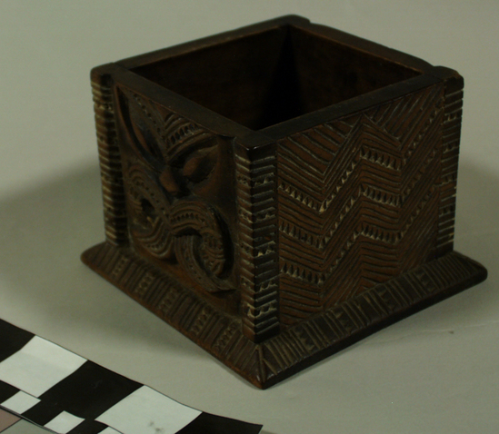 Hearst Museum object 5 of 8 titled Carved wooden box, accession number 11-42799a,b, described as Box and lid, wood, carved in relief, geometric pattern on lid and two sides of box, facial image carved on other two sides of box; tan and brown.