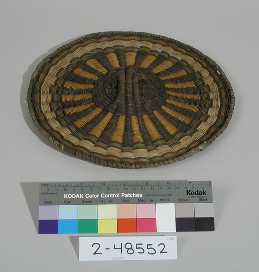 Hearst Museum object titled Plaque, accession number 2-48552, described as Wickerweave; radiating black and yellow lines from black center; alternating green and yellow areas inside perimeter. Made of ribs of sumac or willow twigs, rabbit brush weft, yucca leaf wrapped edge.