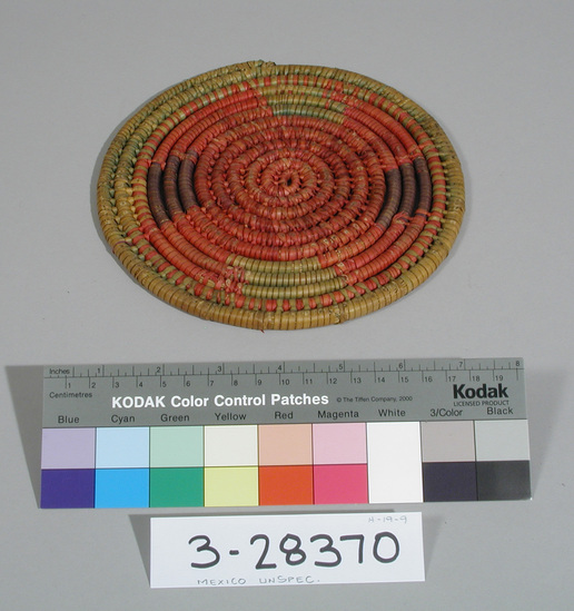 Hearst Museum object titled Pad, accession number 3-28370, described as Hot pad; coiled grass bundle w/ palm leaf wrapping; red center surrounded by alternating green and black areas separated by red; damaged; diam. 19.3 cm. Provenience (incl. craftsman): Mexico unsp. Materials/techniques: Coiled; palm leaf on grass bundle foundation; dyes.