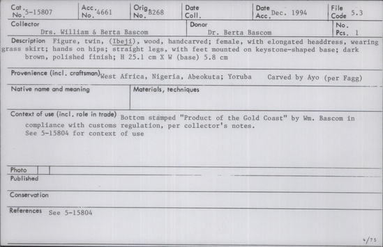 Documentation associated with Hearst Museum object titled Ere ibeji figure, accession number 5-15807, described as Figure, twin (Ibeji), wood, handcarved; female, with elongated headdress, wearing grass skirt; hands on hips; straight legs, with feet mounted on keystone-shaped base; dark brown, polished finish. Bottom stamped "Product of the Gold Coast" by William Bascom in compliance with customs regulation, per collector's notes.