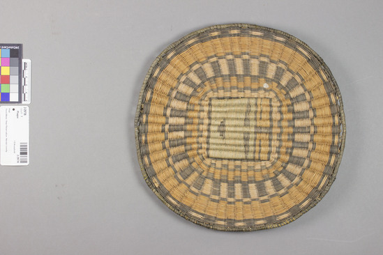 Hearst Museum object 2 of 3 titled Plaque, accession number 2-29736, described as Wicker weave.  Colors:  orange, natural, black, green.  Motif:  katchina face.