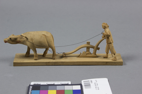 Hearst Museum object titled Figurine, accession number 9-6800, described as Wooden model: farmer plowing with water buffals; length 7 inches. Missing: 1 horn, part of plow, part of farmer's left leg and right hand.