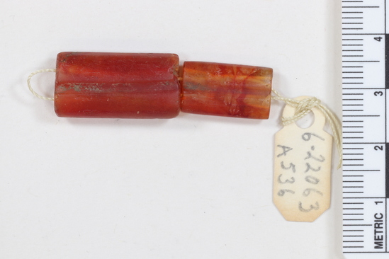 Hearst Museum object titled Beads, accession number 6-22063, described as beads, double-tubular shape for holding necklace, carnelian; length 17 and 22 mm