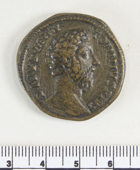 Hearst Museum object 7 of 8 titled Coin: æ sestertius, accession number 8-4879, described as Coin; AE; Sestertius; Roman. 32 mm. Commodus, 180 AD. Rome, Italy. Obverse: DIVVS M ANTONINVS PIVS, bust of Divus Marcus r.. Reverse: CON SE CRATIO, funeral pyre with Marcus Aurelius in quadriga on top; in field, S C.