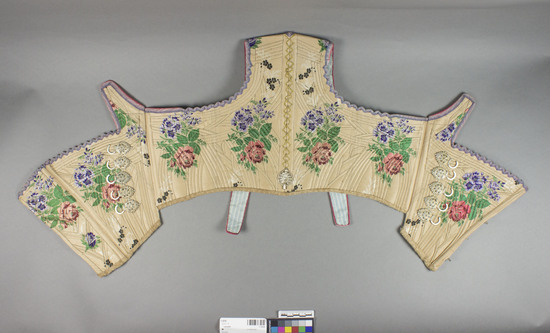 Hearst Museum object titled Corselet, accession number 7-3378, described as corselet; silk; plain weave brocaded; light brown ground; varicolored floral designs; metal wrapped yarns; gilt metal eyelets; purple ribbon binding. Impossible to measure