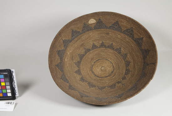 Hearst Museum object 3 of 3 titled Basket, accession number 1-224797, described as Coiled, 3-rod foundation, basin shaped, red-brown designs of two horizontal bands of triangles with points up, circle around center.  Note the anomalous additions to the designs near the closure of the bands. Sedge root and split redbud shoots sewing materials. Starting knot twined.