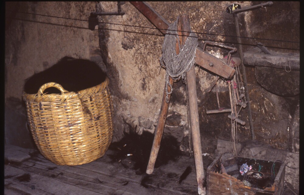 Hearst Museum object titled Color slide, accession number 25-98401, described as 35mm color slide transparency. A basket full of dark yarn, next to a wooden weaving mechanism.