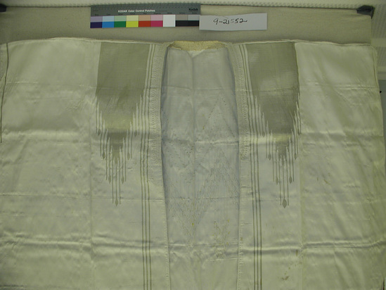 Hearst Museum object titled Robe, accession number 9-21552, described as Man’s robe; off-white, sleeveless robe.  Twill weave; gold supplemental weft designs and braid along front opening, shoulders and armholes; 3 stripes of gold near center of each front; 52.5 cm x 15.75 cm gold chevron with flame-like extensions ending in leaf-like sahpeas at shoulders; supplemental weft gold stripe extending 32 cm from shoulder; 15 cm gold stripe under each armhole; back covered with similar shapes as front; 59 cm x 69.5 cm central panel; 2 9 cm x 48 cm shapes on side of center panel; hem of back has 61 cm x 28.5 cm gold flame-like extensions ending with leaf-like shapes; special braiding around neck edge; paper interfacing on back neckline