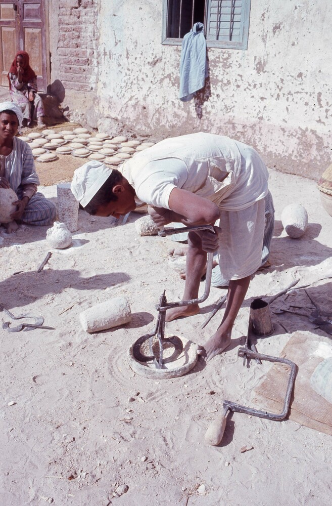 Hearst Museum object titled Color slide, accession number 25-29295, described as 35mm color slide transparency. "Using the iron drill; assembling the bits; grinding away!; tools around workers". Alabaster production.