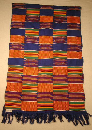 Hearst Museum object titled Shawl, accession number 5-16697, described as Kente cloth shawl; 5 narrow strips sewn together to form a shawl with fringes on each end (blue). colors include golden yellow, green, dark red, royal blue, black and white. alternating patterns of basket like design, colored stripes and solid blue sections.