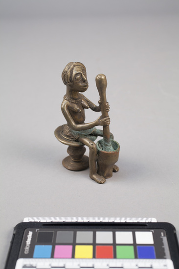 Hearst Museum object titled Figure, accession number 5-3232, described as Brass figure. Seated female using large pounder and mortar.
