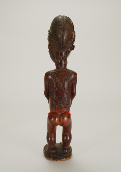 Hearst Museum object 2 of 7 titled Figurine, female, accession number 5-3182, described as carved wooden figure; standing female with hands clasped around protruding umbilicum; string of red beads around thighs;