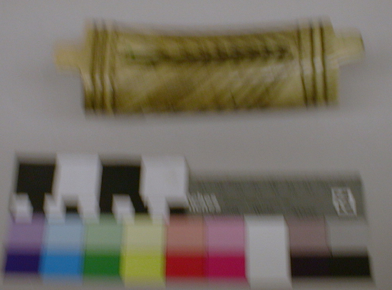 Hearst Museum object titled Money purse, accession number 1-2259, described as Antler, hollow, curved; oval cross section; rectangular longitudinal slot at center; raised flange at each end, with transverse grooves; incised zigzag bands principal design element; tabs at each end on top of purse. Contents: bits of snake skin, medicine root, and feather tipped stick.