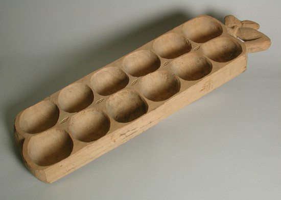 Hearst Museum object 2 of 2 titled Game board, accession number 5-16417, described as Yoruba Warri game board; carved wood; 2 columns of 6 equal sized compartments (for game pieces/rocks); zoomorphic figure on one end of board.