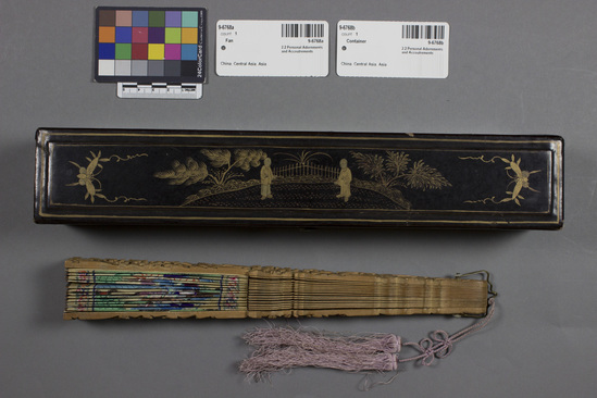 Hearst Museum object 1 of 3 titled Fan, accession number 9-6768a,b, described as (a) Wood and paper fan depicting people painted ivory (?) face and cloth costume; light purple tassels at base; length 11 inches; (b) black and gold lacquer contain; length 12 7/8 inches.