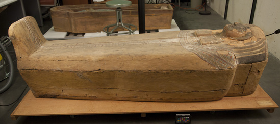 Hearst Museum object 51 of 167 titled Coffin, accession number 6-19912, described as Wooden anthropoid coffin. Inscription running down center of lid. Determined by Kea Johnston to probably be the outer coffin of Iwefaa (6-19928, 12-11039). According to Kea Johnston, "This coffin belonged to a man named Iwefaa, whose name is inserted in the middle of the spells written in the two columns on the front. This coffin is likely the outer coffin for PAHMA 6-19928 based on the similarity of the owner's name, unusual costume, and the paleography of the inscription. Both coffins were purchased on the antiquities market by George Reisner for Phoebe A Hearst. However, stylistically, they are very similar to a set of coffins known to have come from the site of Akhmim, which was excavated in the 1880s by Gaston Maspero, and which has heavily looted for the antiquities market during this decade." "The pectoral vignette between the text and the collar shows the deceased standing before squatting baboon and is the source of our logo. The hieroglyph for 'sky' is above their heads, and the side borders are formed by a pyramid and the symbol for the West.