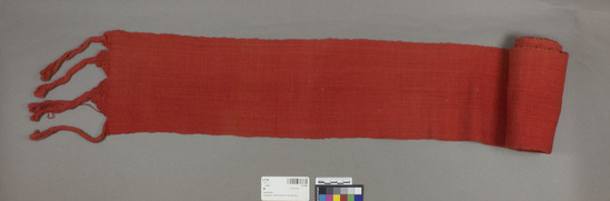 Hearst Museum object titled Sash, accession number 3-27369, described as sash; red-dyed cotton; l. 2.2 M. not incl. tassels, w. 15.8 cm.