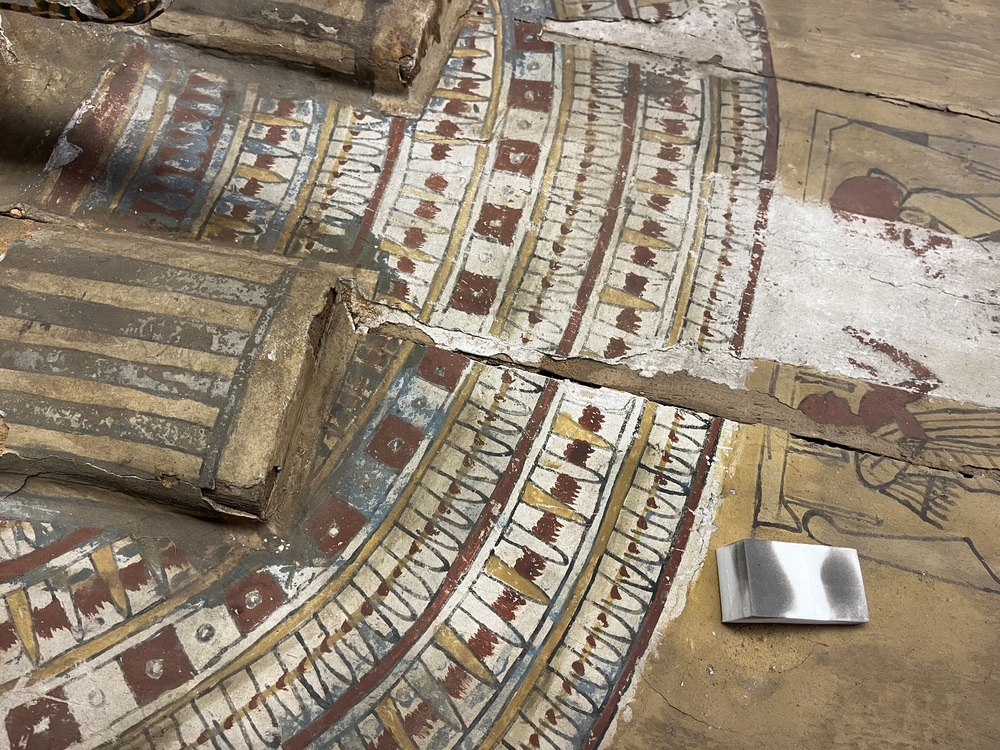 Hearst Museum object 162 of 167 titled Coffin, accession number 6-19912, described as Wooden anthropoid coffin. Inscription running down center of lid. Determined by Kea Johnston to probably be the outer coffin of Iwefaa (6-19928, 12-11039). According to Kea Johnston, "This coffin belonged to a man named Iwefaa, whose name is inserted in the middle of the spells written in the two columns on the front. This coffin is likely the outer coffin for PAHMA 6-19928 based on the similarity of the owner's name, unusual costume, and the paleography of the inscription. Both coffins were purchased on the antiquities market by George Reisner for Phoebe A Hearst. However, stylistically, they are very similar to a set of coffins known to have come from the site of Akhmim, which was excavated in the 1880s by Gaston Maspero, and which has heavily looted for the antiquities market during this decade." "The pectoral vignette between the text and the collar shows the deceased standing before squatting baboon and is the source of our logo. The hieroglyph for 'sky' is above their heads, and the side borders are formed by a pyramid and the symbol for the West.