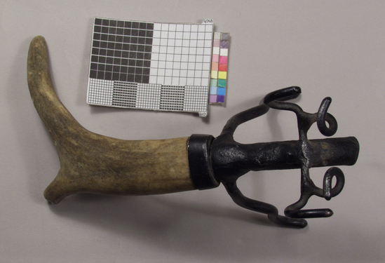 Hearst Museum object 2 of 2 titled Corkscrew, accession number 2-69023, described as Caplifter, zoomorphic; antler handle in shape of hind legs; wrought iron forelegs, head, and antlers in shape of deer, lower jaw serves as crown caplifter, painted black; 14.6 cm long.