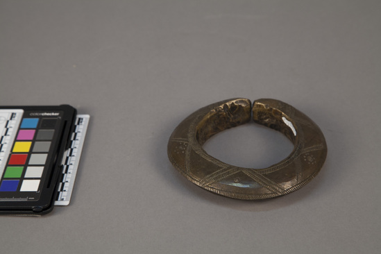 Hearst Museum object 2 of 2 titled Bangle bracelet, accession number 5-16970, described as brass bangle bracelet.  very heavy, solid, brass hammered to triangular knife-like edge.  split ring.  cross hatched pattern with dots.  rough interior surface.