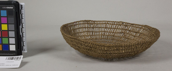 Hearst Museum object 2 of 2 titled Basket, accession number 1-211517, described as Openwork dish-shaped basket.  Tag "NW Calif".  Second tag "Klamath R. Tribes Att.". Per Ralph Shanks:  Twined openwork basket. The basket has a crossed warp starting knot.  The warp and weft material is hazel or willow.  At the start there is some reddish plant material.  The basket is plain twined over primarily one warp, with the rows spaced approximately .5 inch apart. The rim is trimmed.  The basket has an up to the right slant of weft twist and a rightward work direction.  The workface is on the exterior.  The basket is from Northwestern California.