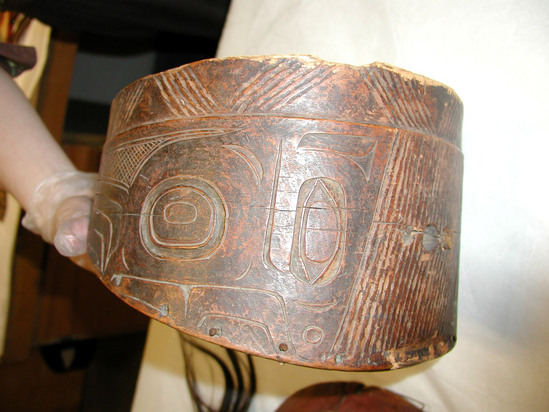 Hearst Museum object titled Face shield, accession number 2-19082, described as Wooden "beaver" (face protector) with totemic design. Shallow notches cut into the upper rim are eye holes. Accompanies 2-19081 (war helmet). Label: "fighting headdress and collar carving represents a worm, the same tradition as feast pipe.