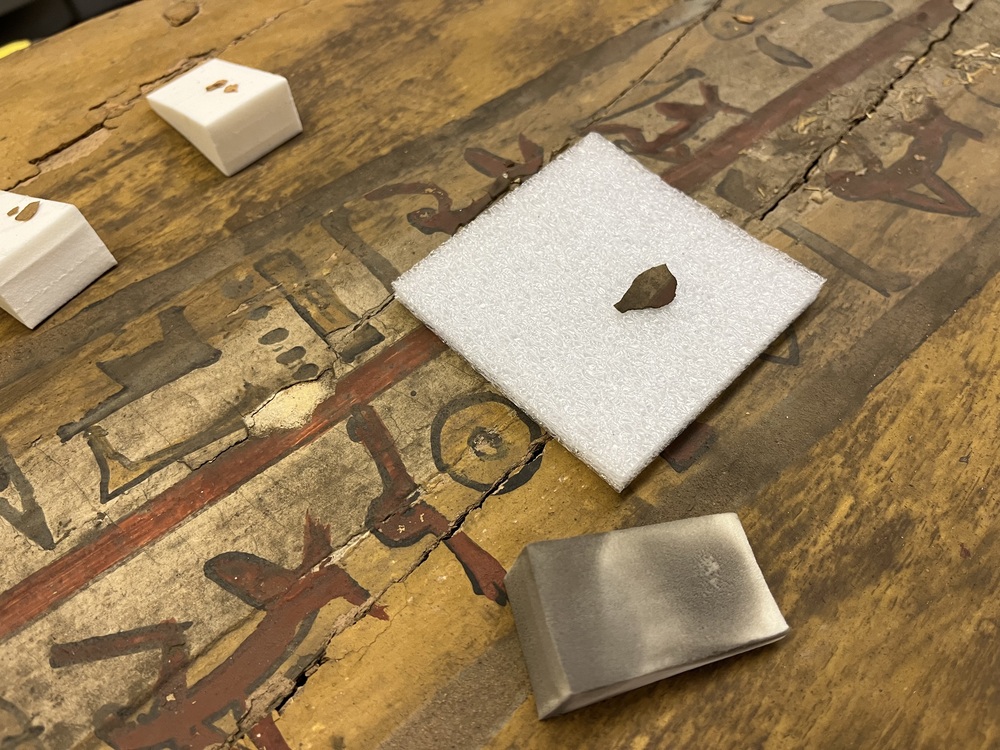 Hearst Museum object 4 of 167 titled Coffin, accession number 6-19912, described as Wooden anthropoid coffin. Inscription running down center of lid. Determined by Kea Johnston to probably be the outer coffin of Iwefaa (6-19928, 12-11039). According to Kea Johnston, "This coffin belonged to a man named Iwefaa, whose name is inserted in the middle of the spells written in the two columns on the front. This coffin is likely the outer coffin for PAHMA 6-19928 based on the similarity of the owner's name, unusual costume, and the paleography of the inscription. Both coffins were purchased on the antiquities market by George Reisner for Phoebe A Hearst. However, stylistically, they are very similar to a set of coffins known to have come from the site of Akhmim, which was excavated in the 1880s by Gaston Maspero, and which has heavily looted for the antiquities market during this decade." "The pectoral vignette between the text and the collar shows the deceased standing before squatting baboon and is the source of our logo. The hieroglyph for 'sky' is above their heads, and the side borders are formed by a pyramid and the symbol for the West.