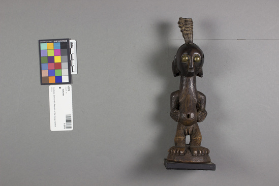 Hearst Museum object titled Statuette, accession number 5-2578, described as Wooden statuette of female; brass eyes, horn stuck in top of head; on commercial black painted metal base. Height 23.5 cm.