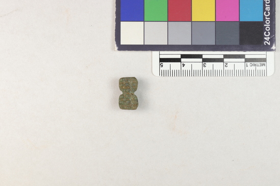 Hearst Museum object 3 of 6 titled Amulet, accession number 5-14003, described as Amulet: hourglass shaped with raised squares on front. Greenish brown with hole through back.