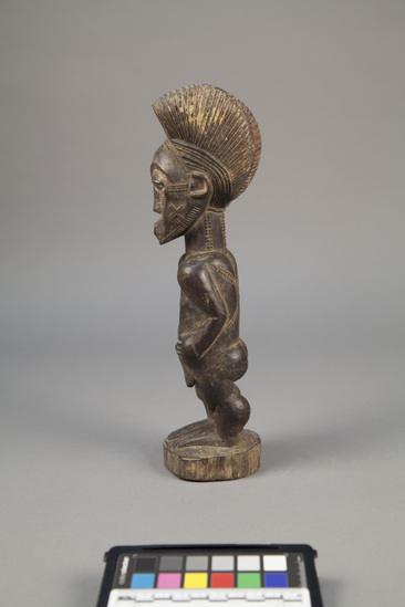 Hearst Museum object titled Figure, accession number 5-7682, described as Figure; wood; female, standing, with hands on stomach; elaborate incised hair-do; hatch markings  on face, neck and back; white filled eyes; protruding navel; Heavy general wear, split down back. Evaluation: $ 700.00