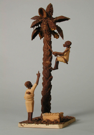 Hearst Museum object titled Thorn carving, accession number 5-11424, described as thorn carving; man harvesting oil palm kernels from tree, watched and directed by woman on the ground;  mounted on base of soft wood, which is covered with darkbrown shavings of thorns;  26 cm. h.;  9 cm. w.