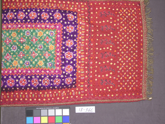 Hearst Museum object titled Shawl, accession number 18-366, described as Tie-dyed cotton textile; metallic thread fringe; red ground with planet and star-like designs in center. Probably “Plangi” and “Trikit.” 28 x 80 inches not including fringe.