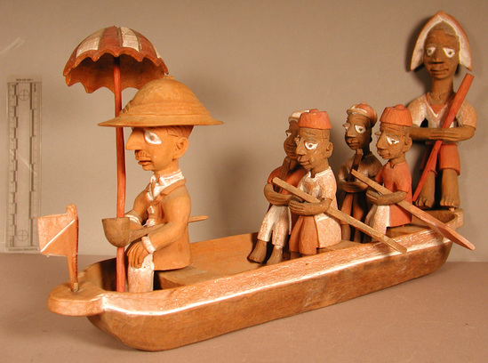 Hearst Museum object 9 of 15 titled Figures, accession number 5-16237a-q, described as caricature figure group; caricature of a District Officer on tour; carved & painted wood a - boat, has bag of frags b - Dist. officer (front) c - poler (rear) d - paddler (LF) e - paddler (LR) f - paddler (RF) g - paddler (RR) h - hat i - umbrella handle j - umbrella k - flag l - pipe m - pole n - paddle (RF) o - paddle (LF) p - paddle (LR) q - paddle (RR) Found two pegs in a bag with this object number.