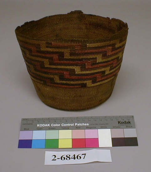 Hearst Museum object titled Basket, accession number 2-68467, described as Round with flat bottom, straight sides, wide band of false embroidery in linear design, faded red and yellow and dark brown; badly broken in upper area. Spruce root, grass stems, dyed, plain twined, wicker weave. Filled voids with pulp mixture, tinted fills with acrylic paint.