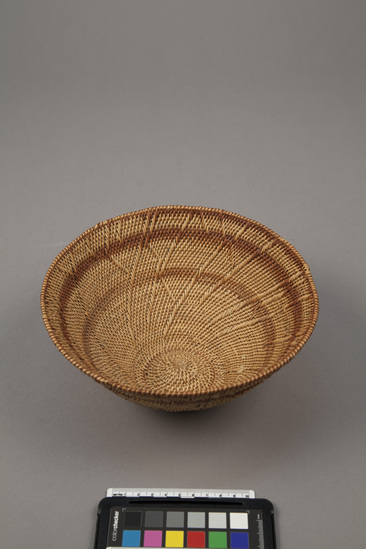 Hearst Museum object titled Basket, accession number 5-16999, described as Round, conical, woven, basket with narrow, convex base.  Close woven of willow or similar, in natural shade w/ 2 brown bands and a brown and natural rim.  Using a double stitch, a pattern is formed similar to small tree branches.  1987?