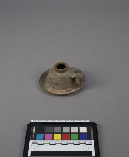 Hearst Museum object titled Lamp, accession number 5-16896, described as Soldered tin lamp made from a gasoline tinniken.  Body of lamp formed by top and spout of can.  Circular base and strap handle are attached.  A key-hole on handle facilitated hanging the lamp from a wall.