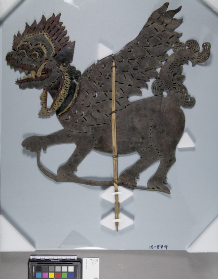 Hearst Museum object titled Shadow puppet, accession number 18-879, described as shadow puppet; Singa (lion); tanned stiffened leather cut to traditional pattern; small decorative cutouts; painted various colors; mounted on carved wood stick; used as puppet in wajang kulit performances; held in front of light, behind screen, moved