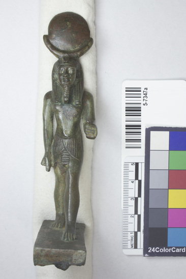 Hearst Museum object titled Figurine, accession number 5-7347a, described as Figurine of Re; solid cast bronze; walking Re; wears kilt; sun symbol, beard and uraeus; traces of red and green paint; gold at eye corners; projection for securing to standard; height 14 cm, length 5.6 cm, width 3.3 cm