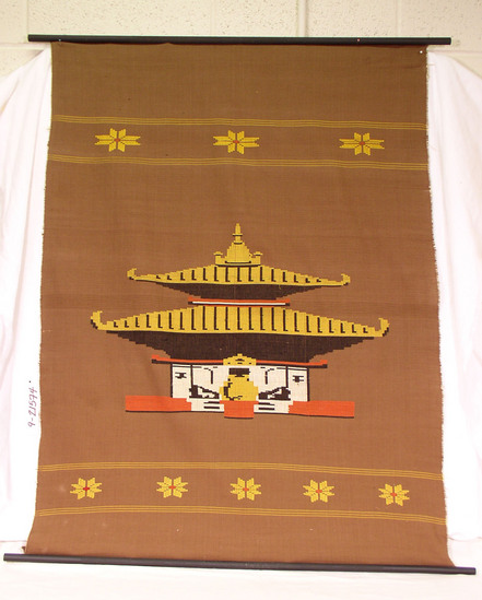 Hearst Museum object titled Wall hanging, accession number 9-21574, described as Wall hanging; brown cotton with woven designs in yellow, rust black and ecru. Temple in center; yellow bands and flowers at each end; mounted on two black wooden polls.