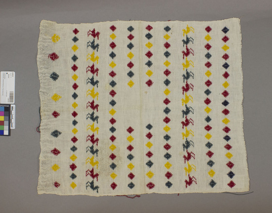 Hearst Museum object titled Huipil, accession number 3-28125, described as Year old child’s blouse.  Cotton.  Open basket weave, brocaded.  White ground, yellow, red, and green designs.  Bird, lozenge motifs. 9.5 inches x 16 inches.