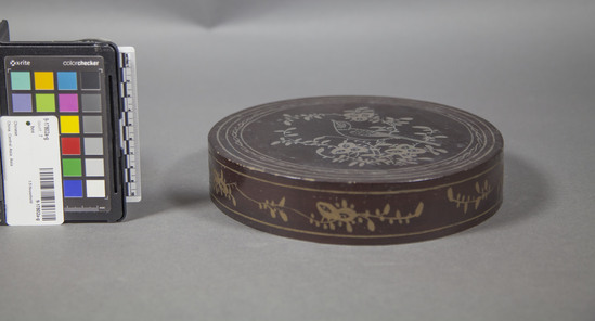 Hearst Museum object 5 of 13 titled Box, accession number 9-17802a-g, described as box (sweetmeat); wood, black lacquer exterior, painted gold birds and flowers on lid; body with painted floral sprigs; painted gold interior; lid and box with scholar and aide in black; five enamelled metal insert trays, each with one of the five Immortals in landscape scene. “Nade Inohina” (Made in China) stamped on bottom of each tray; early 20th century