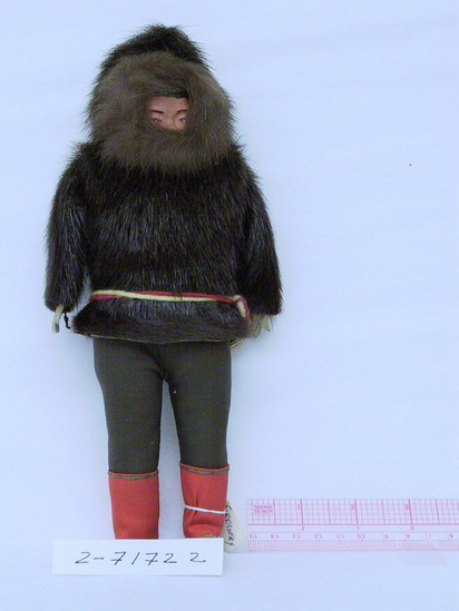 Hearst Museum object titled Doll, accession number 2-71722, described as Eskimo man doll. Stuffed cloth doll, with head of ceramic material, molded and painted feathers and hair. Dressed in sealskin parka, brown fabric trousers, red leggings and light tan mukluks, and a red and yellow yarn belt. Has leather hands. Height: 10 inches.