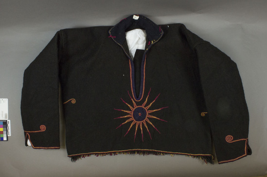 Hearst Museum object 3 of 3 titled Jacket, accession number 3-11, described as Jacket (coton); black wool; fulled to appear felted; fringed along bottom of back side; red and yellow embroidery; also dark blue ribbon binding and applique; inside collar of dark blue wool; approximately 45 cm long, 106 cm around bottom