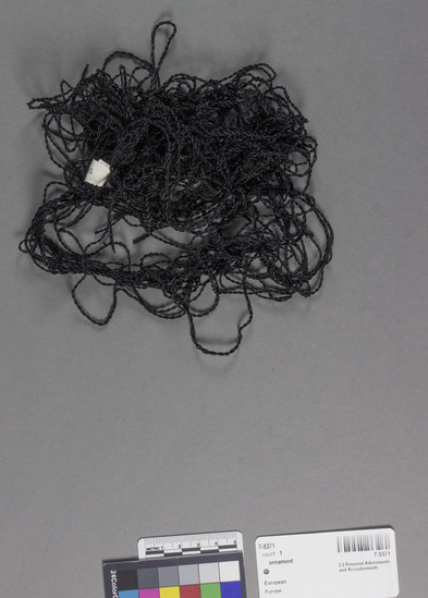 Hearst Museum object titled Ornament, accession number 7-5371, described as ornament for hair; rayon thread black; multiple twisted strands knotted together at one end; shell ornament attached; maximum length ca. 44 centimeters