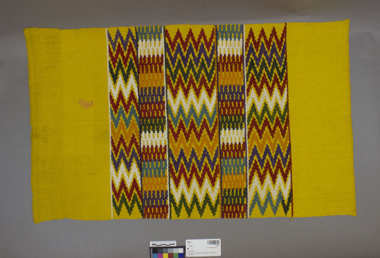 Hearst Museum object titled Huipil, accession number 3-28087, described as Blouse material.  Cotton.  Plain weave, brocaded.  Yellow ground, varicolored designs.  Zigzag, block motifs 28 inches x 16.5 inches