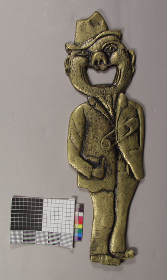 Hearst Museum object titled Corkscrew, accession number 2-69005, described as Caplifter, brass, anthropomorphic; figure of man with hat dressed in shabby clothing with mouth as opening for crown caplifter; 20.3 cm long.