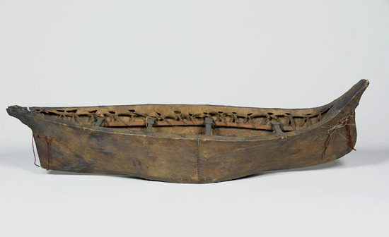 Hearst Museum object titled Boat model, accession number 2-6424a,b, described as Model of open skin boat (umiak). Sail missing (1975). wooden frame covered with skin; bow characteristic of Pacific Eskimo; fabric sail, sewn from three pieces attached to two wooden mast poles.