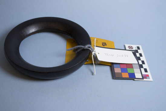 Hearst Museum object titled Stand, accession number EOC2019.456, described as Ring (possibly stand for rounded bottom pot) made of single piece of dark wood that is carved and polished.