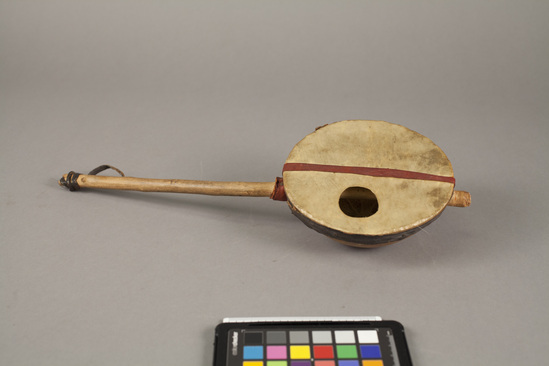 Hearst Museum object titled Banjo, accession number 5-14094a,b, described as Banjo. Gourd bowl with wood handle. Handle attached to bowl by passing through holes on side. Bowl covered with leather, black leather band around upper edge, red leather strip across center. Hole in top of bowl at one side. Handle wrapped with black and red leather. Bowl diameter: 12 cm; handle length: 36 cm;